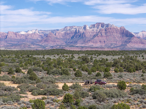 Aerial view of a SUV pulling a teardrop camper trailer on a dirt road across Gooseberry Mesa with red rock cliffs of Zion National Park in the background Hurricane Utah United States. Aerial view of a SUV pulling a teardrop camper trailer on a dirt road across Gooseberry Mesa with red rock cliffs of Zion National Park in the background Hurricane Utah United States.