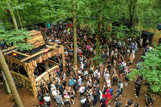 Herzogenaurach Germany 27 July 2025 Aerial view of the Open Beatz Festival with a large crowd gathered around a wooden stage nestled among dense green trees in a forest. Herzogenaurach Germany 27 July 2025 Aerial view of the Open Beatz Festival with a large crowd gathered around a wooden stage nestled among dense green trees in a forest.
