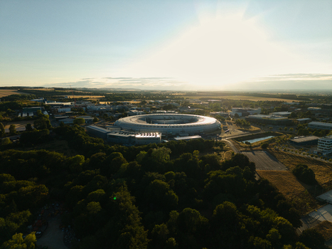 Aerial view of Diamond Light Source a circular synchrotron facility surrounded by greenery under golden hour light in Didcot United Kingdom.