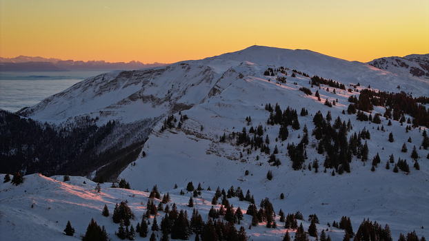 Aerial view of Col de la Faucille mountain pass with snow covered slopes and pine trees under a golden sunset sky Gex Auvergne Rhone Alpes France. Aerial view of Col de la Faucille mountain pass with snow covered slopes and pine trees under a golden sunset sky Gex Auvergne Rhone Alpes France.