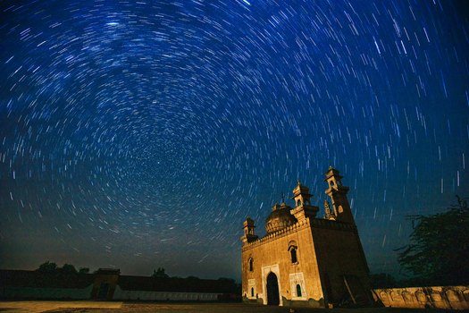 View of the Abbasi Mosque main gate at Derawar Fort under a vibrant night sky with circular star trails showcasing historic architecture in Derawar Punjab Pakistan.