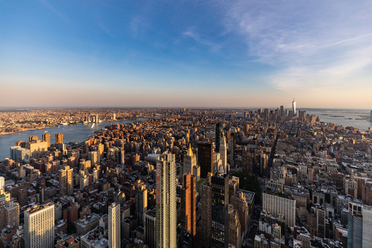View of the dense Manhattan skyline at sunset with One World Trade Center and the East River in New York New York United States. View of the dense Manhattan skyline at sunset with One World Trade Center and the East River in New York New York United States.
