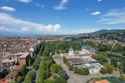 Aerial view of Castello del Valentino surrounded by lush greenery of Parco del Valentino and the Po River with the city skyline and Alps in the distance Torino Piemonte Italy. Aerial view of Castello del Valentino surrounded by lush greenery of Parco del Valentino and the Po River with the city skyline and Alps in the distance Torino Piemonte Italy.
