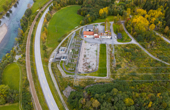 Aerial view of an electrical substation with power lines a nearby river and a road surrounded by autumn forest in Andalsnes More og Romsdal Norway. Aerial view of an electrical substation with power lines a nearby river and a road surrounded by autumn forest in Andalsnes More og Romsdal Norway.