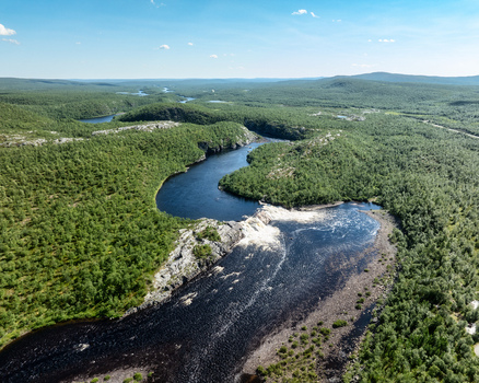 Aerial view of Pikefossen falls with the winding river flowing through the dense green forest landscape in Kautokeino Finnmark Norway. Aerial view of Pikefossen falls with the winding river flowing through the dense green forest landscape in Kautokeino Finnmark Norway.