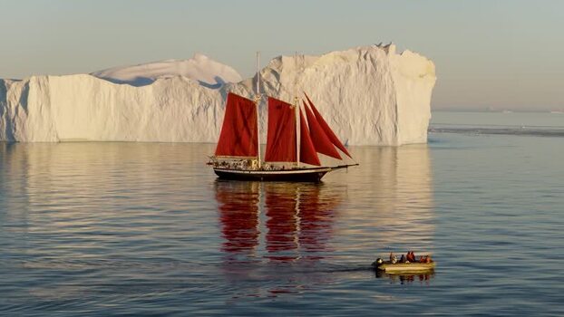 Aerial view of red sailed schooner near iceberg Greenland. Aerial view of red sailed schooner near iceberg Greenland.