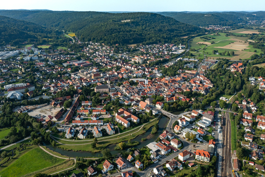 Aerial view of Ebermannstadt town center with red roofed houses the Wiesent river and lush green hills under a clear sky Ebermannstadt Bavaria Germany. Aerial view of Ebermannstadt town center with red roofed houses the Wiesent river and lush green hills under a clear sky Ebermannstadt Bavaria Germany.