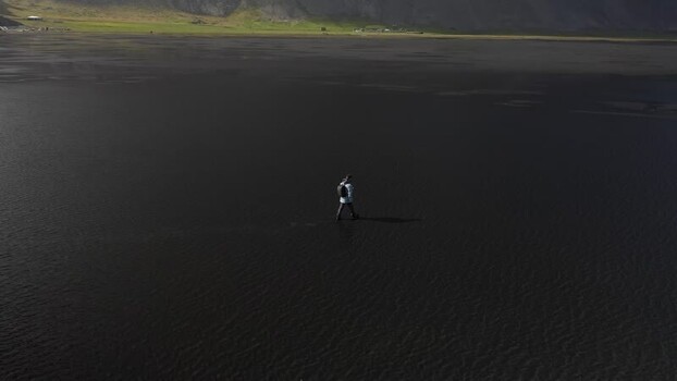 Aerial view of a person walking on the black sand beach Iceland.