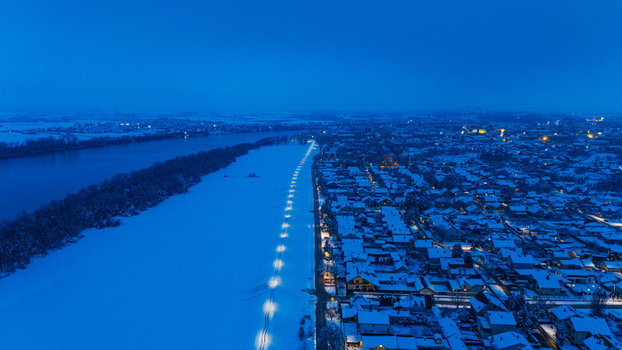 Aerial view of the snow covered town of Sremska Mitrovica along the Sava River at dusk with illuminated streetlights in Sremska Mitrovica Vojvodina Serbia.