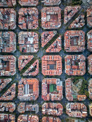 Aerial view of the iconic grid patterned city blocks with chamfered corners and red tiled roofs in the Eixample district of Barcelona Catalonia Spain. Aerial view of the iconic grid patterned city blocks with chamfered corners and red tiled roofs in the Eixample district of Barcelona Catalonia Spain.
