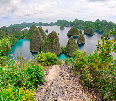 View of karst islands rising from turquoise waters in Raja Ampat Southwest Papua Indonesia.