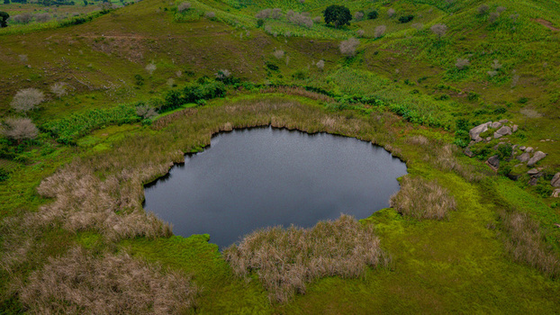 Aerial view of a volcanic crater lake surrounded by lush green hills and grassy slopes in Mangu Plateau Nigeria. Aerial view of a volcanic crater lake surrounded by lush green hills and grassy slopes in Mangu Plateau Nigeria.