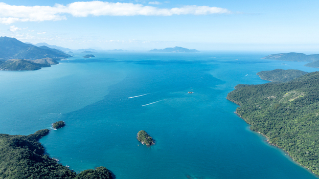 Aerial view of Lagoa Azul also known as Blue Lagoon featuring turquoise waters lush green islands and boat wakes under a clear blue sky in Angra dos Reis Rio de Janeiro Brazil.
