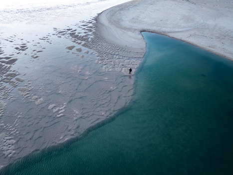 Aerial view of Lagoa de Obidos with a person standing on the sandbank near turquoise waters and textured sand patterns in Foz do Arelho Leiria District Portugal. Aerial view of Lagoa de Obidos with a person standing on the sandbank near turquoise waters and textured sand patterns in Foz do Arelho Leiria District Portugal.