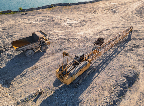 Le Pouzin Auvergne Rhone Alpes France 04 July 2026 Aerial view of a Liebherr HS 845 crawler crane and articulated dump truck at a quarry near a body of water.
