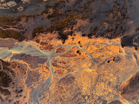 Aerial view of braided glacial river channels with sediment and volcanic soil illuminated by golden hour light in Iceland. Aerial view of braided glacial river channels with sediment and volcanic soil illuminated by golden hour light in Iceland.