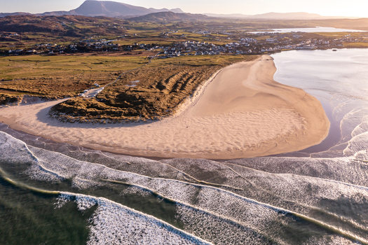 Aerial view of Sheephaven Bay with its expansive sandy beach rolling dunes and gentle waves under soft golden hour light in Dunfanaghy County Donegal Ireland. Aerial view of Sheephaven Bay with its expansive sandy beach rolling dunes and gentle waves under soft golden hour light in Dunfanaghy County Donegal Ireland.