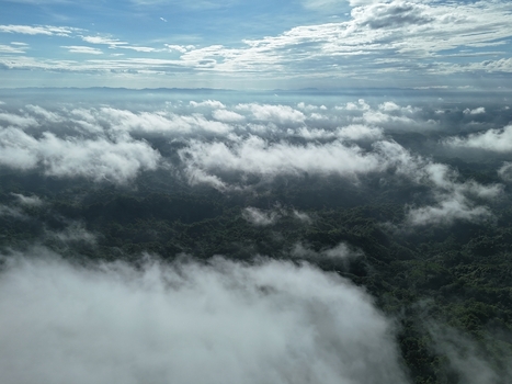 Aerial view of the lush forested hills of Sitakund partially obscured by low hanging clouds and mist under a bright sky in Sitakund Chittagong Division Bangladesh. Aerial view of the lush forested hills of Sitakund partially obscured by low hanging clouds and mist under a bright sky in Sitakund Chittagong Division Bangladesh.