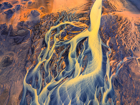 Aerial view of a braided glacial river system with sediment rich water channels flowing through dark volcanic terrain in Iceland. Aerial view of a braided glacial river system with sediment rich water channels flowing through dark volcanic terrain in Iceland.