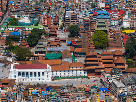 Aerial view of the historic Kathmandu Durbar Square featuring traditional pagoda style temples the white neoclassical Gaddi Baithak palace and dense urban surroundings in Nepal.