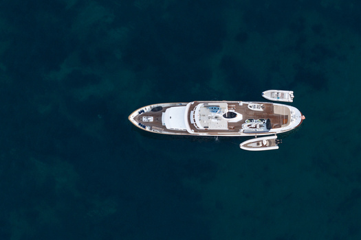 Aerial view of a luxury yacht anchored in the deep blue Mediterranean Sea with two small tender boats alongside in Cannes Provence Alpes Cote d Azur France. Aerial view of a luxury yacht anchored in the deep blue Mediterranean Sea with two small tender boats alongside in Cannes Provence Alpes Cote d Azur France.