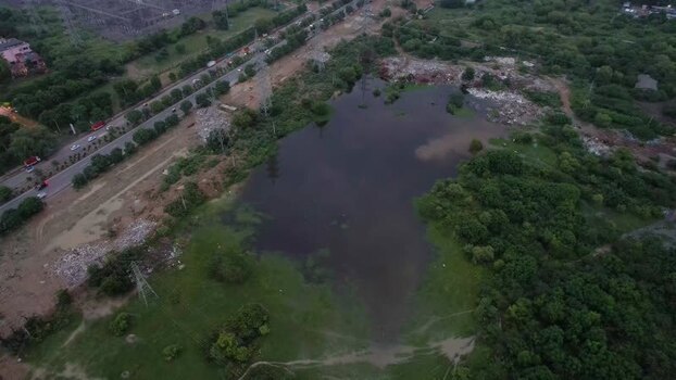 Aerial view of pond near road and urban development in India.