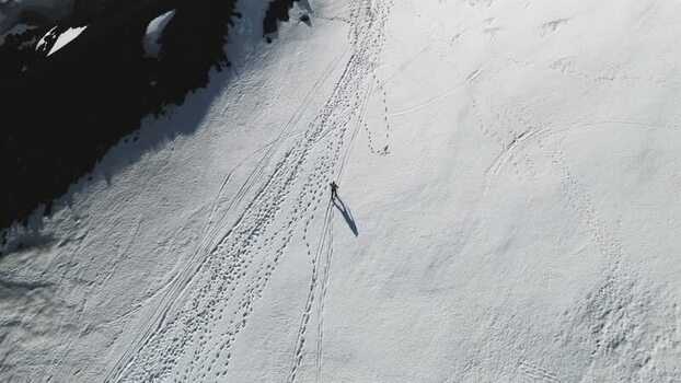 Aerial view of a person walking on a snowy slope near Rifugio Sapienza Italy. Aerial view of a person walking on a snowy slope near Rifugio Sapienza Italy.
