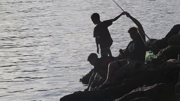View of people fishing from rocky shore in Rio de Janeiro Brazil.