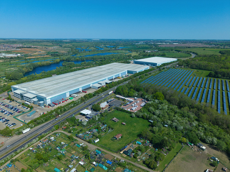 Aerial view of a large industrial warehouse complex a solar farm and allotment gardens under a clear blue sky in Little Irchester England United Kingdom. Aerial view of a large industrial warehouse complex a solar farm and allotment gardens under a clear blue sky in Little Irchester England United Kingdom.