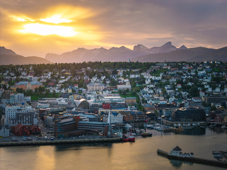 Aerial view of Tromso city skyline at sunset with mountains in the background harbor buildings and calm water in Tromso Troms Norway.