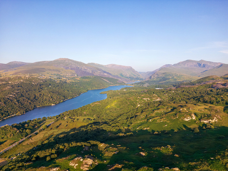 Aerial view of Llyn Padarn surrounded by the lush green mountains of Snowdonia under a clear blue sky in Cwm y glo Wales United Kingdom. Aerial view of Llyn Padarn surrounded by the lush green mountains of Snowdonia under a clear blue sky in Cwm y glo Wales United Kingdom.