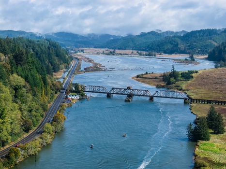 Aerial view of the Coos Bay Rail Line crossing the Siuslaw River near Florence Oregon with salmon fishing boats wetlands forest and coastal transportation routes.