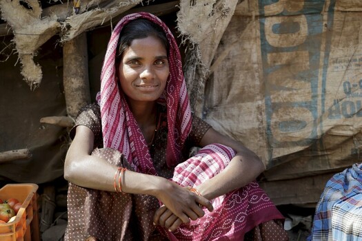 Odisha India 26 March 2026 View of a woman with a red and white patterned shawl her eyes reflecting the soft light sitting in front of a makeshift dwelling. Odisha India 26 March 2026 View of a woman with a red and white patterned shawl her eyes reflecting the soft light sitting in front of a makeshift dwelling.