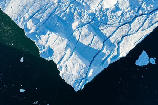 Aerial view of the Ilulissat glacier featuring deep crevasses and bright white ice floating in dark arctic waters Greenland. Aerial view of the Ilulissat glacier featuring deep crevasses and bright white ice floating in dark arctic waters Greenland.