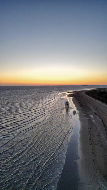 Aerial view of the historic Burnham on Sea Low Lighthouse standing on the sandy beach at sunset with calm waves and a golden horizon in Burnham on Sea England United Kingdom. Aerial view of the historic Burnham on Sea Low Lighthouse standing on the sandy beach at sunset with calm waves and a golden horizon in Burnham on Sea England United Kingdom.