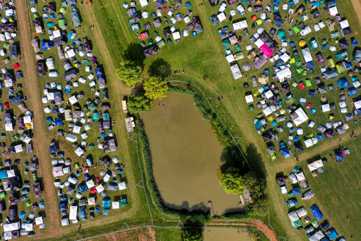 Herzogenaurach Germany 24 July 2025 Aerial view of the Open Beatz Festival campsite with numerous colorful tents pitched on green fields during a sunny day.