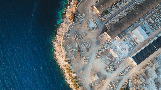 Aerial view of Jadrankamen stone quarry with white limestone blocks and industrial warehouses along the turquoise Adriatic coast Pucisca Splitsko dalmatinska Croatia. Aerial view of Jadrankamen stone quarry with white limestone blocks and industrial warehouses along the turquoise Adriatic coast Pucisca Splitsko dalmatinska Croatia.