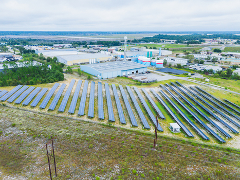 Aerial view of a solar farm with rows of photovoltaic panels industrial warehouses and power lines in a rural landscape in Wilmington North Carolina United States. Aerial view of a solar farm with rows of photovoltaic panels industrial warehouses and power lines in a rural landscape in Wilmington North Carolina United States.