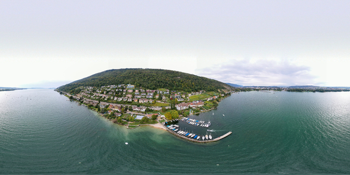 Aerial view of Lake Biel featuring a small marina with boats and residential houses nestled on a lush green hillside in Biel Bienne Canton of Bern Switzerland. Aerial view of Lake Biel featuring a small marina with boats and residential houses nestled on a lush green hillside in Biel Bienne Canton of Bern Switzerland.