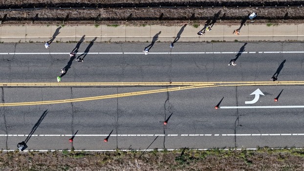 Aerial view of people walking and running along an asphalt road with lane markings and traffic cones in Boulder Colorado United States. Aerial view of people walking and running along an asphalt road with lane markings and traffic cones in Boulder Colorado United States.