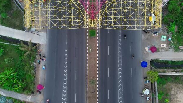 Aerial view of highway with yellow metal arch in Indonesia.