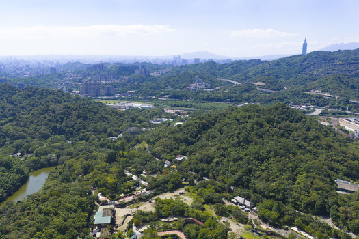 Aerial view of the lush green hills and forested landscape surrounding the Taipei Zoo with the Taipei 101 skyscraper visible in the distance in Taipei City Taiwan. Aerial view of the lush green hills and forested landscape surrounding the Taipei Zoo with the Taipei 101 skyscraper visible in the distance in Taipei City Taiwan.
