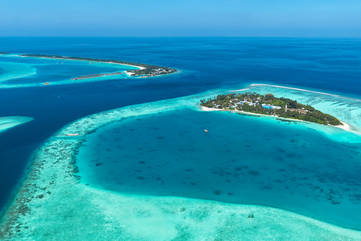 Aerial view of the tropical island of Vaanee surrounded by shallow turquoise lagoon waters and coral reefs in Vaanee Dhaalu Atoll Maldives. Aerial view of the tropical island of Vaanee surrounded by shallow turquoise lagoon waters and coral reefs in Vaanee Dhaalu Atoll Maldives.