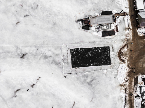 Aerial view of a hole cut into the frozen surface of a lake in Trakai surrounded by snow and ice with a nearby wooden structure and path in Trakai Vilnius County Lithuania. Aerial view of a hole cut into the frozen surface of a lake in Trakai surrounded by snow and ice with a nearby wooden structure and path in Trakai Vilnius County Lithuania.