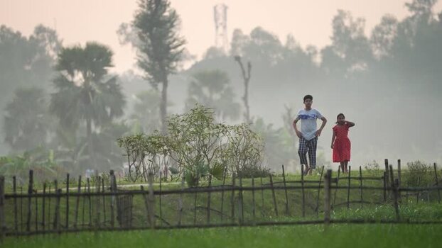 View of children walking behind a bamboo fence in Bogura Bangladesh.
