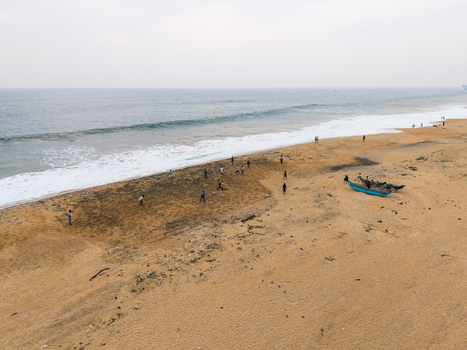 Aerial view of people playing football on a sandy beach with wooden fishing boats under an overcast sky in Galle Southern Province Sri Lanka.