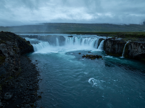 Aerial view of Godafoss Waterfall with cascading water flowing over rocky cliffs into a turquoise river under a cloudy sky in Thingeyjarsveit Iceland. Aerial view of Godafoss Waterfall with cascading water flowing over rocky cliffs into a turquoise river under a cloudy sky in Thingeyjarsveit Iceland.