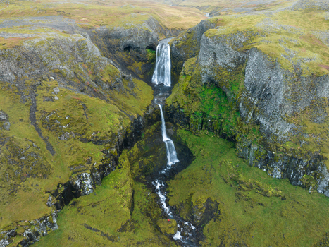 Aerial view of the cascading waterfall plummets down the rugged cliffs embraced by vibrant green moss Snæfellsnes Eyja og Miklaholtshreppur Iceland. Aerial view of the cascading waterfall plummets down the rugged cliffs embraced by vibrant green moss Snæfellsnes Eyja og Miklaholtshreppur Iceland.