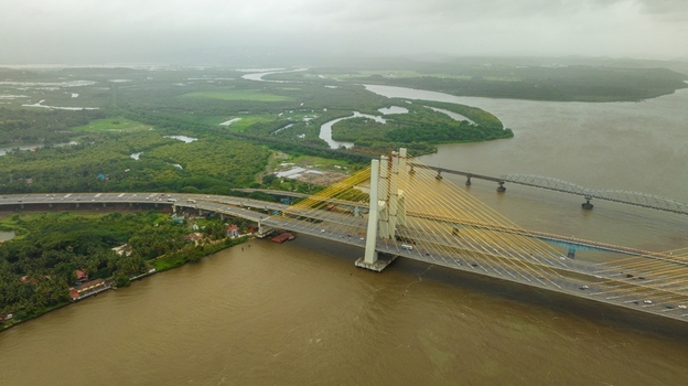 Aerial view of the Zuari Bridge spanning the river with lush mangrove forests and overcast sky in Cortalim Goa India.