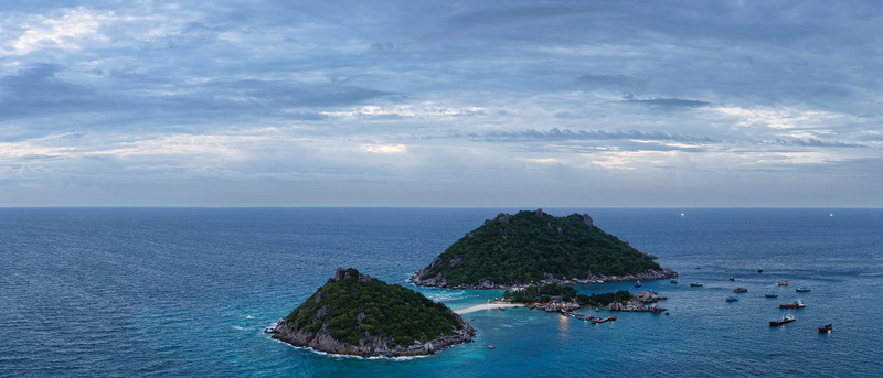 Aerial view of Nang Yuan Island with its iconic sandbar connecting lush green hills surrounded by turquoise waters and small boats Ko Tao Surat Thani Thailand.